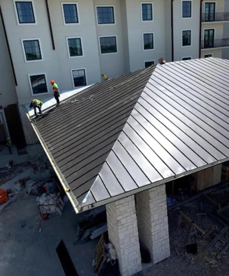 Crew installing standing seam metal roof panels on a commercial project in Charlotte